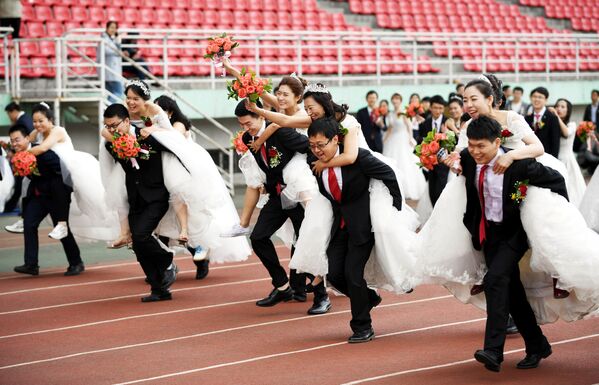 Пары принимают участие в конкурсе во время массовой свадьбы в Китае