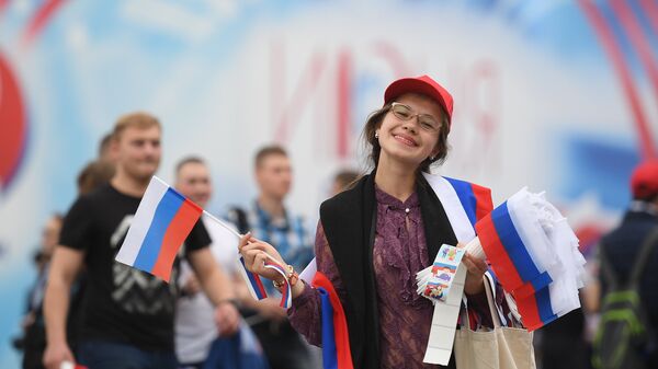 Девушка раздает флажки перед началом праздничного концерта, посвященного Дню России