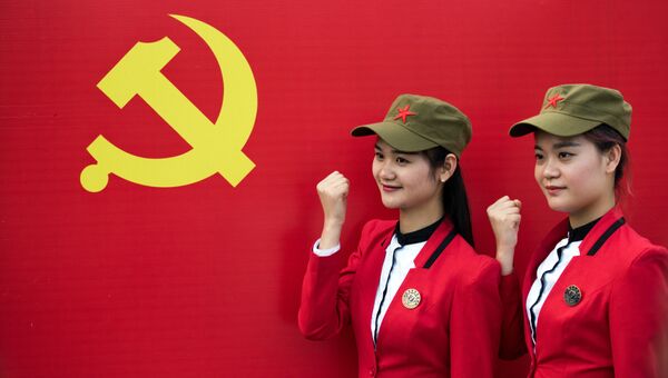 Девушки фотографируются с флагом Коммунистической партии Китая в Шаошане. Архивное фото