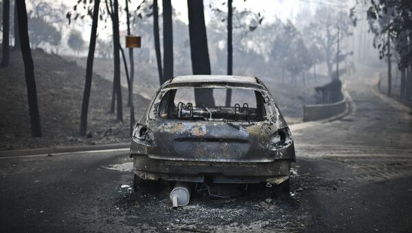 Сгоревшая машина на дороге после лесного пожара в Педрогао, в центральной Португалии, 18 июня 2017