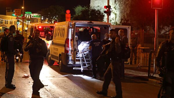 Израильские медики несут тело одного из трех палестинцев, которые совершили нападение на израильскую девушку полицейского в Иерусалиме