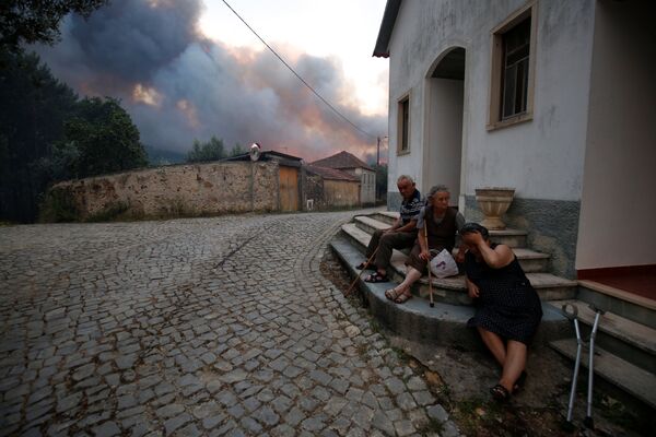 Местные жители сидят возле дома во время лесных пожаров в Португалии