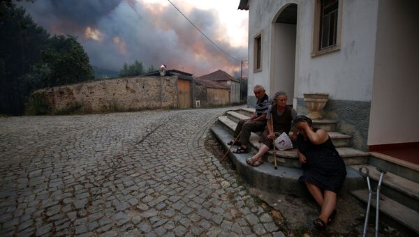 Местные жители сидят возле дома во время лесных пожаров в Португалии