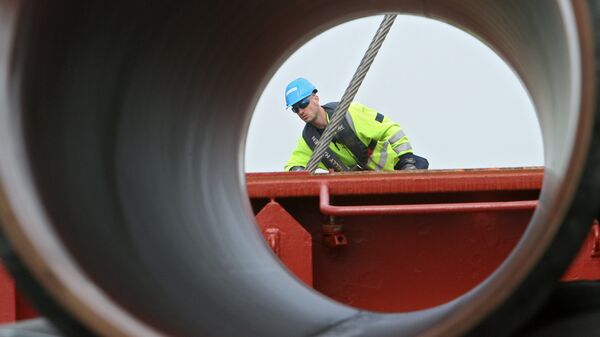 Рабочие подготовливают трубы для строящегося газопровода Северный поток к погрузке на судно доставки