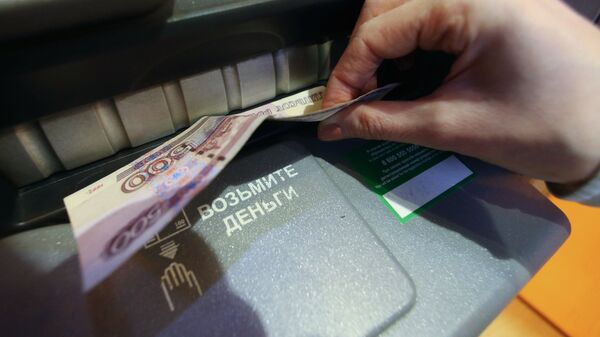 Женщина получает наличные деньги из банкомата в отделении Сбербанка РФ в Калининграде