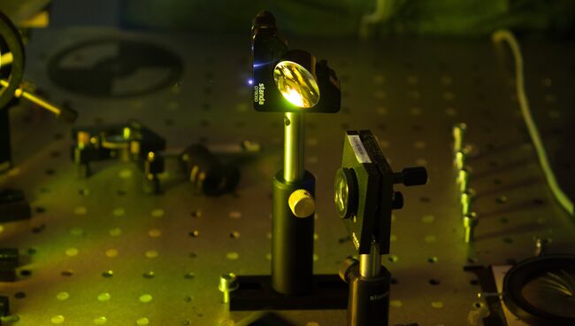 Линза голографической камеры, созданной российскими физиками, и лазерная искра (слева)