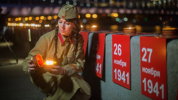 Участница патриотической акции Линия памяти зажигает свечу на Крымской набережной вдоль Москвы-реки в память о погибших в Великой Отечественной войне