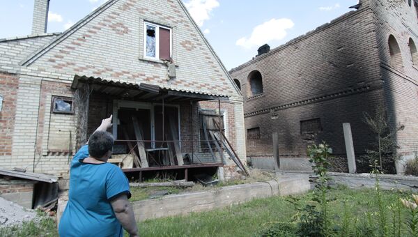 Местная жительница возле дома, пострадавшего от минометного артобстрела поселка Александровка в Донецкой области. 22 июня 2017