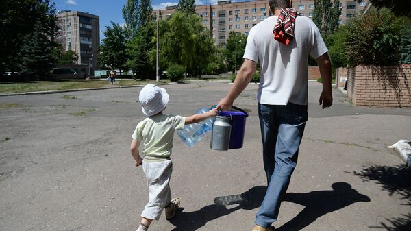 Местные жители с ведрами и канистрами идут к месту подвоза питьевой воды в Донецке