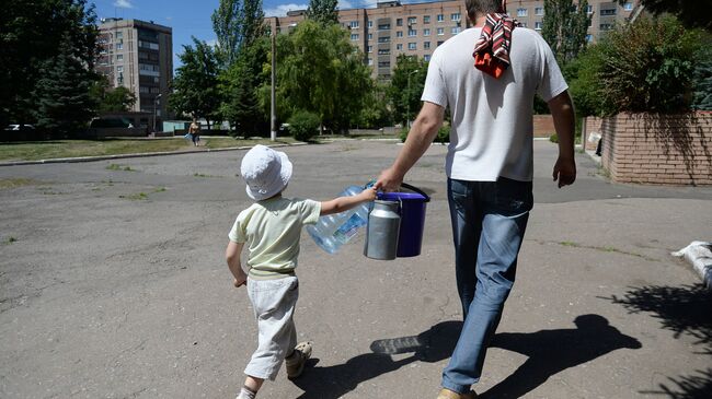 Местные жители с ведрами и канистрами идут к месту подвоза питьевой воды