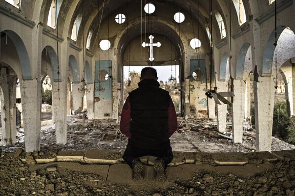 Житель одной из деревень провинции Эль-Хасаке молится в храме Святого Георгия, разрушенного боевиками ИГ.  Сирия, 08.12.2015