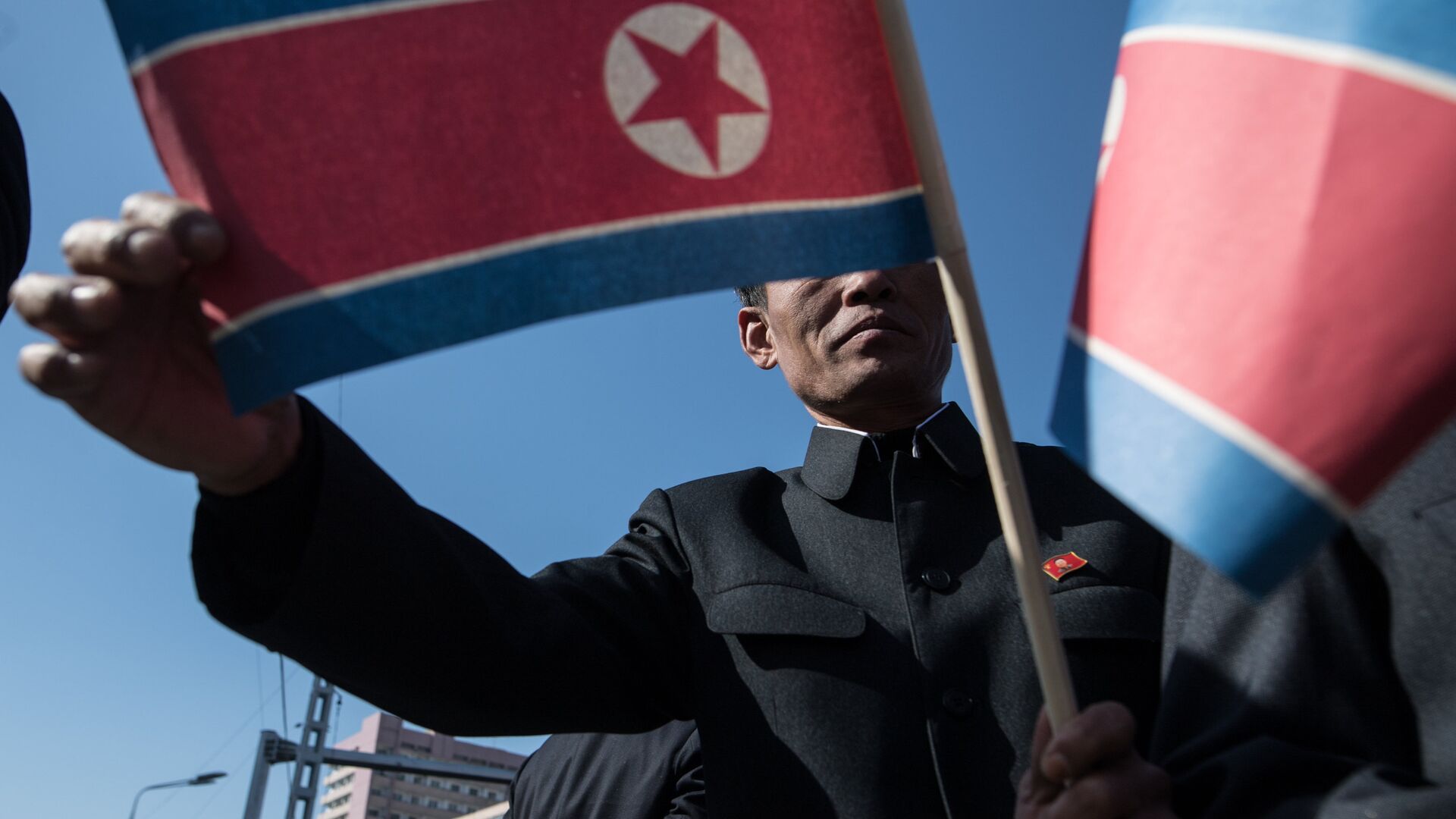 Мужчина с флагом КНДР в Пхеньяне - РИА Новости, 1920, 30.08.2021