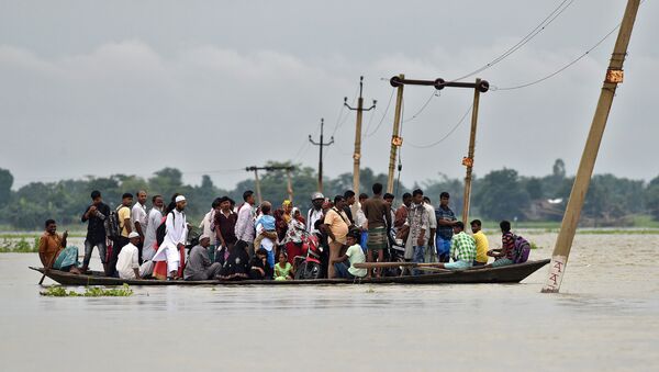 Жители деревни используют лодку, чтобы пересечь затопленную дорогу в деревне штата Ассам, Индия. 4 июля 2017