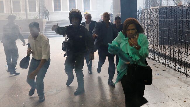 Военнослужащий помогает людям покинуть здание Национального собрания Венесуэлы в Каракасе