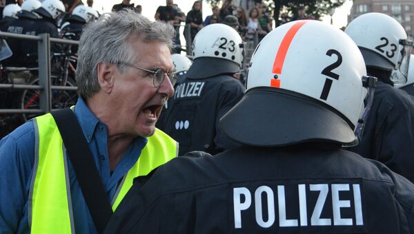 Участник акции протеста (слева) в преддверии саммита G20 в Гамбурге