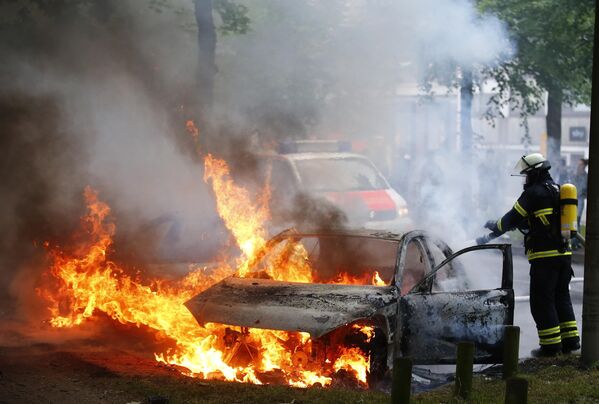 Тушение автомобиля после акций протестов против саммита G20 в Гамбурге