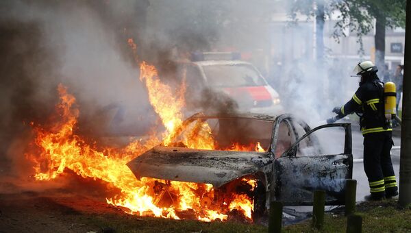Тушение автомобиля после акций протестов против саммита G20 в Гамбурге