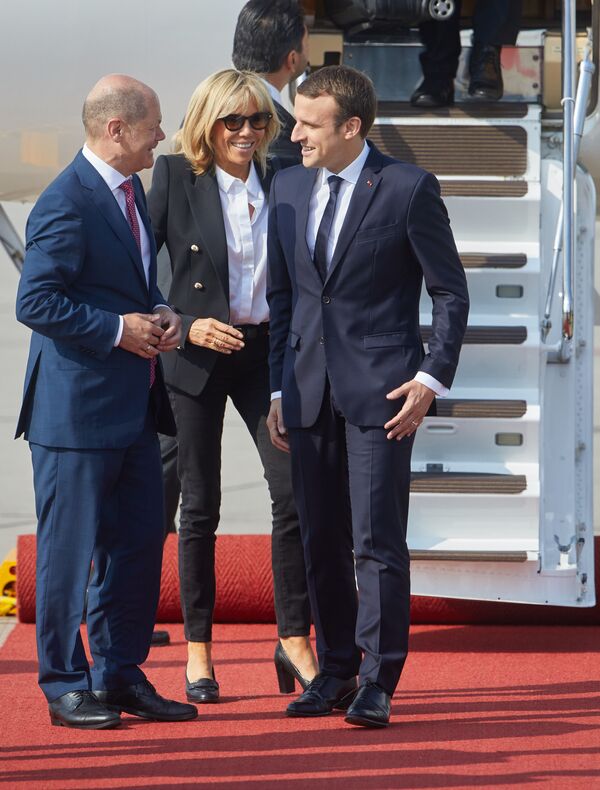 Мэр Гамбурга Олаф Шольц приветствует президента Франции Эммануэля Макрона и его супругу Брижит Тронье в аэропорту Гамбурга