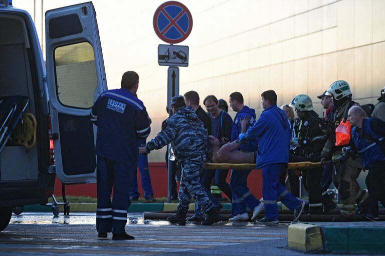 Сотрудники медицинской службы эвакуируют пострадавшего с места пожара в здании торгового центра РИО на Дмитровском шоссе в Москве