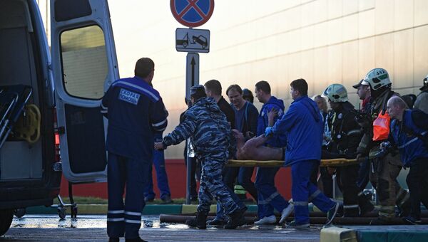 Сотрудники медицинской службы эвакуируют пострадавшего с места пожара в здании торгового центра РИО на Дмитровском шоссе в Москве