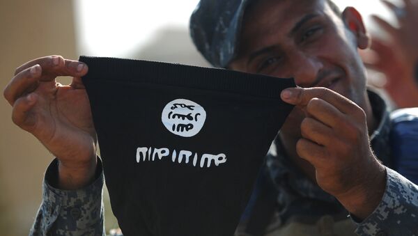 Иракский полицейский держит маску с флагом ИГ* (группировка Исламское государство, запрещена в РФ) в Мосуле. 9 июля 2017