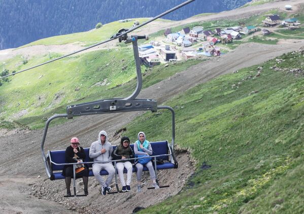 Туристы на кресельном подъемнике всесезонного горного курорта Домбай