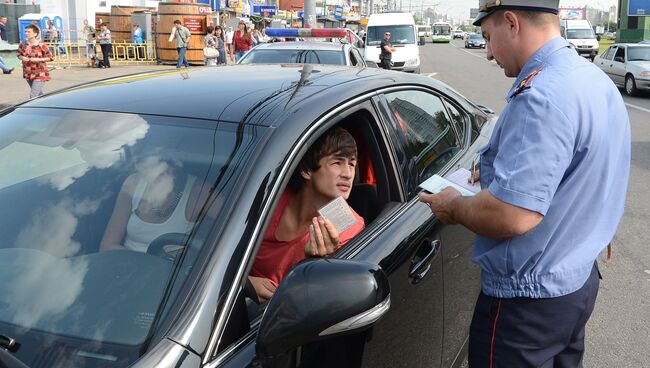 Сотрудник ГИБДД проверяет документы у автовладельца. Архивное фото