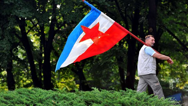 Мужчина с флагом Социалистической Федеративной Республики Югославия в Белграде