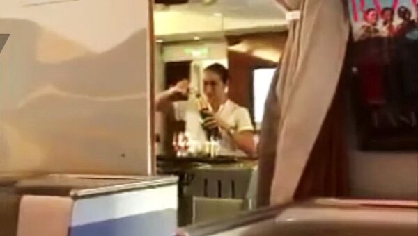 Стоп-кадр из видео, на котором стюардесса авиакомпании Emirates переливает шампанское на борту самолета