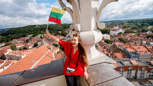 Девушка позирует с флагом Литвы на фоне Вильнюса. Архивное фото