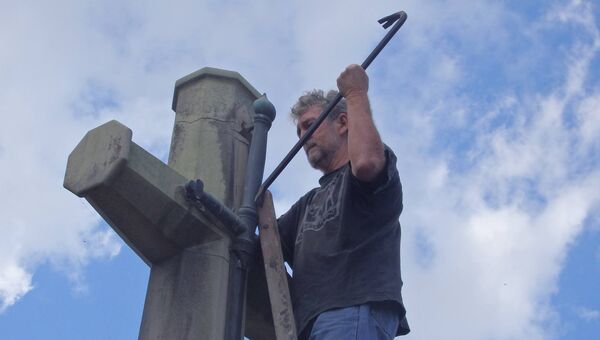 Джозеф Даулинг демонтирует меч с креста на военном мемориале в Брисбене, Австралия
