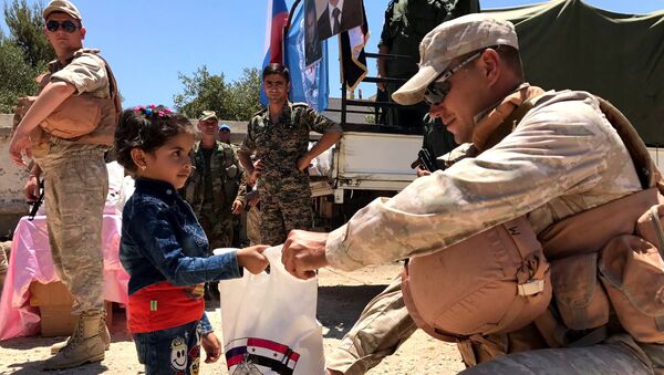 Военнослужащие российского центра по примирению враждующих сторон раздают гуманитарную помощь в сирийской провинции Кунейтра