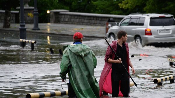 Работники коммунальной службы открывают решетки ливневой канализации на улице во Владивостоке
