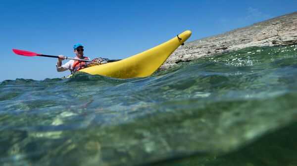 Турист плывет на каяке вдоль берега Черного моря на мысе Тарханкут в Крыму