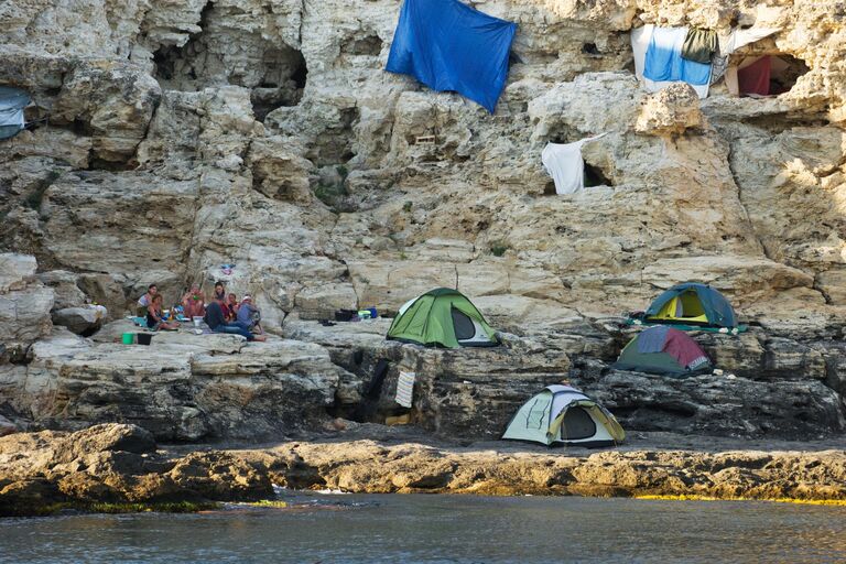 Туристы на берегу Черного моря вблизи Большого Атлеша на мысе Тарханкут в Крыму