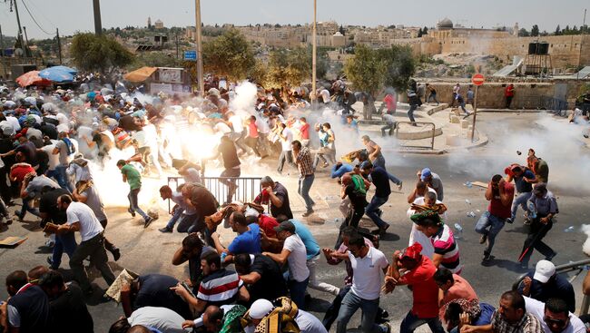 Палестинцы бегут от слезоточивого газа, распыленного израильскими военными после пятничной молитвы на улице за пределами старого города Иерусалима. 21 июля 2017