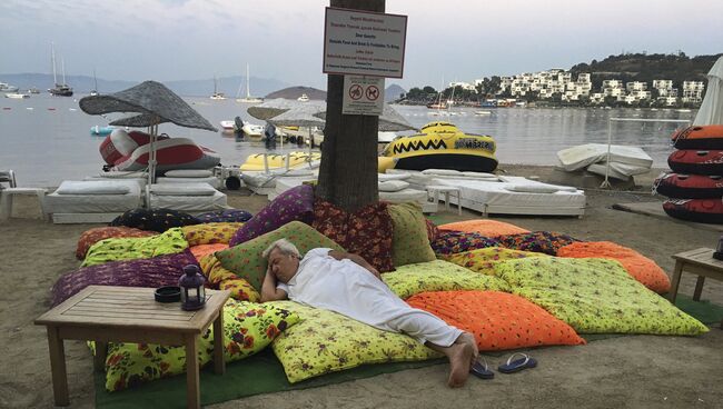 Мужчина спит в пляжной зоне после того как покинул отель во время землетрясения близ турецкого города Бодрум