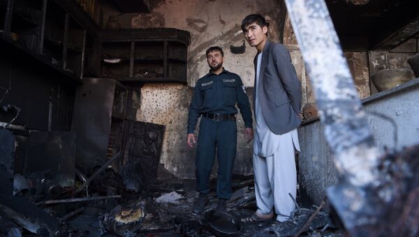 Афганский полицейский и местный житель на месте взрыва в Кабуле, 24 июля 2017