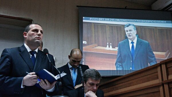 Бывший президент Украины Виктор Янукович (на экране монитора) во время видеотрансляции на экране монитора в Святошинском районном суде Киева. Архивное фото