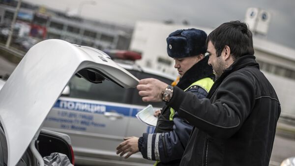 Сотрудник ГИБДД проверяет багажник автомобиля водителя в рамках рейда скрытых патрулей ДПС в Москве