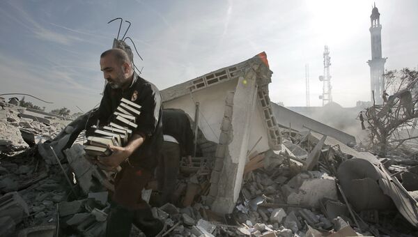 Мужчина выносит стопки Корана из разрушенного взрывом здания в Газе