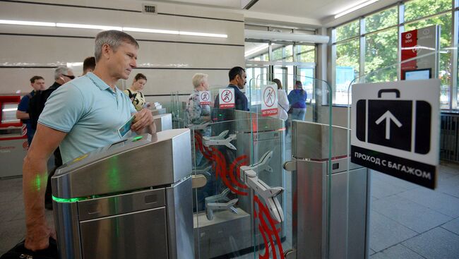 Пассажиры проходит через турникеты на одной из станций метро в Москве. Архивное фото