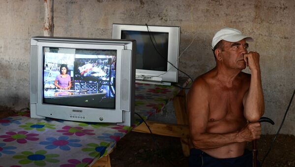 Мужчина смотрит телевизор на территории лагеря для беженцев с востока Украины. Архивное фото