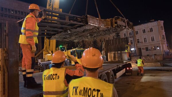 Рабочие выгружают элементы конструкции монумента Стена скорби в месте его установки на пересечении проспекта Академика Сахарова и Садового кольца