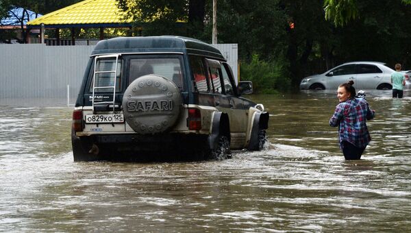 Женщина у автомобиля на затопленной улице Уссурийска. 7 августа 2017