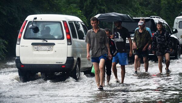 Мужчины и автомобили на затопленной улице в Приморье
