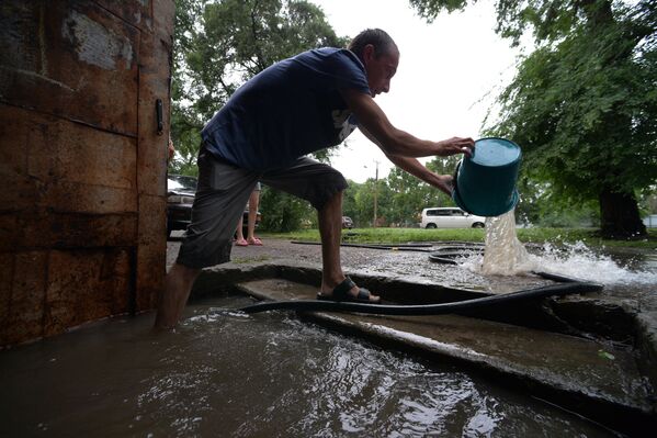 Мужчина вычерпывает воду из подъезда на затопленной улице Уссурийска. 7 августа 2017