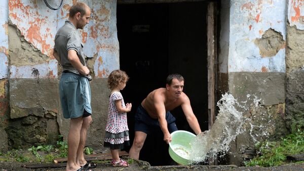 Мужчина вычерпывает воду из подъезда на затопленной улице в Приморье. Архивное фото