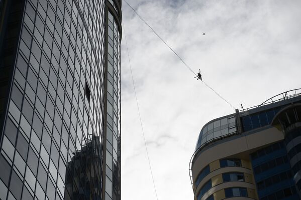 Канатоходец Максим Кагин идет по стропе, натянутой на высоте 126 метров между двумя небоскребами жилого комплекса Чемпион Парк, в Екатеринбурге