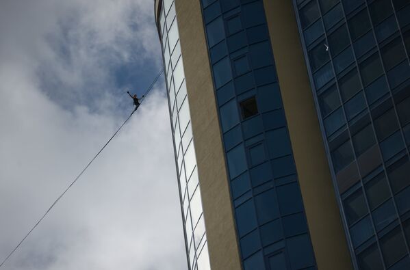 Канатоходец Максим Кагин идет по стропе, натянутой на высоте 126 метров между двумя небоскребами жилого комплекса Чемпион Парк, в Екатеринбурге